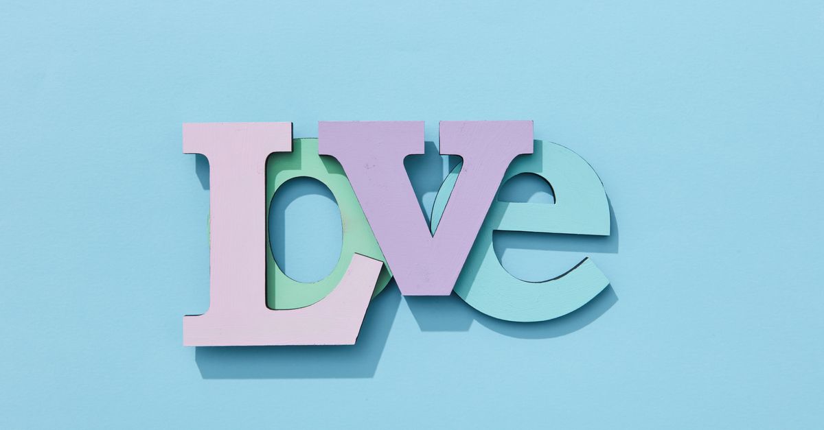 Pastel-colored wooden letters spelling 'LOVE' on a bright blue background, creating a playful vibe.